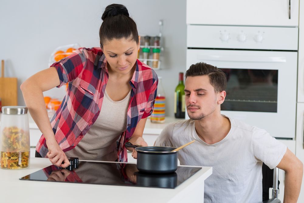 Woman Helping a Man Cook Food on the Stove — Empowering You Disability Services In Maryborough, QLD