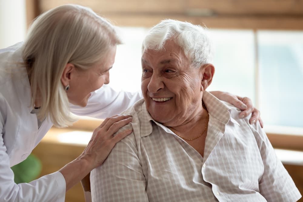 A Nurse is Putting Her Arm Around an Elderly Man 's Shoulder — Empowering You Disability Services In Hervey Bay, QLD