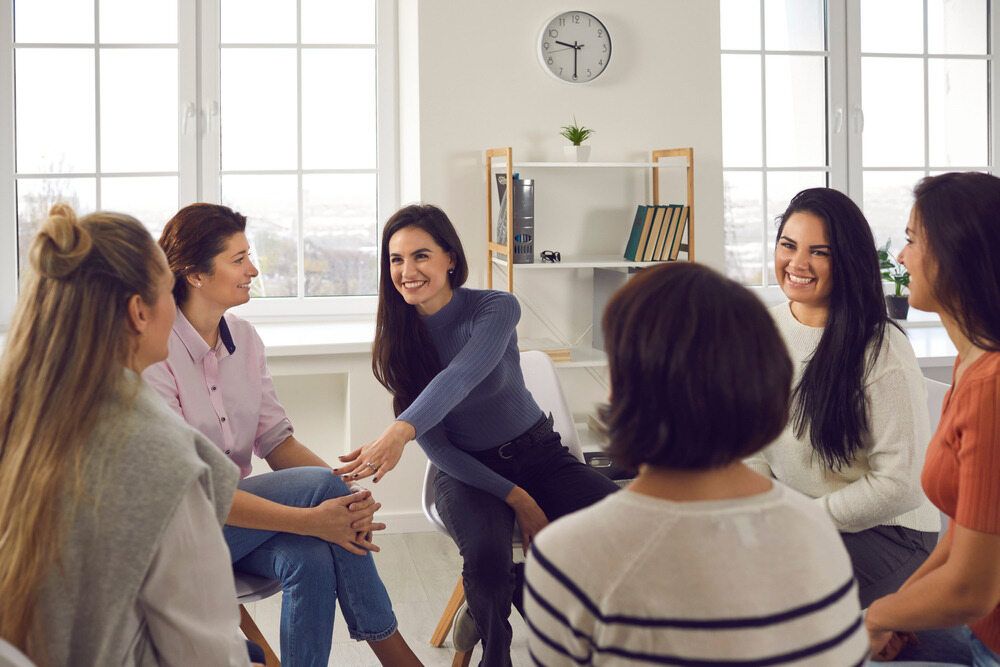 A Group of Women Are Sitting in a Circle Talking to Each Other — Empowering You Disability Services In Maryborough, QLD