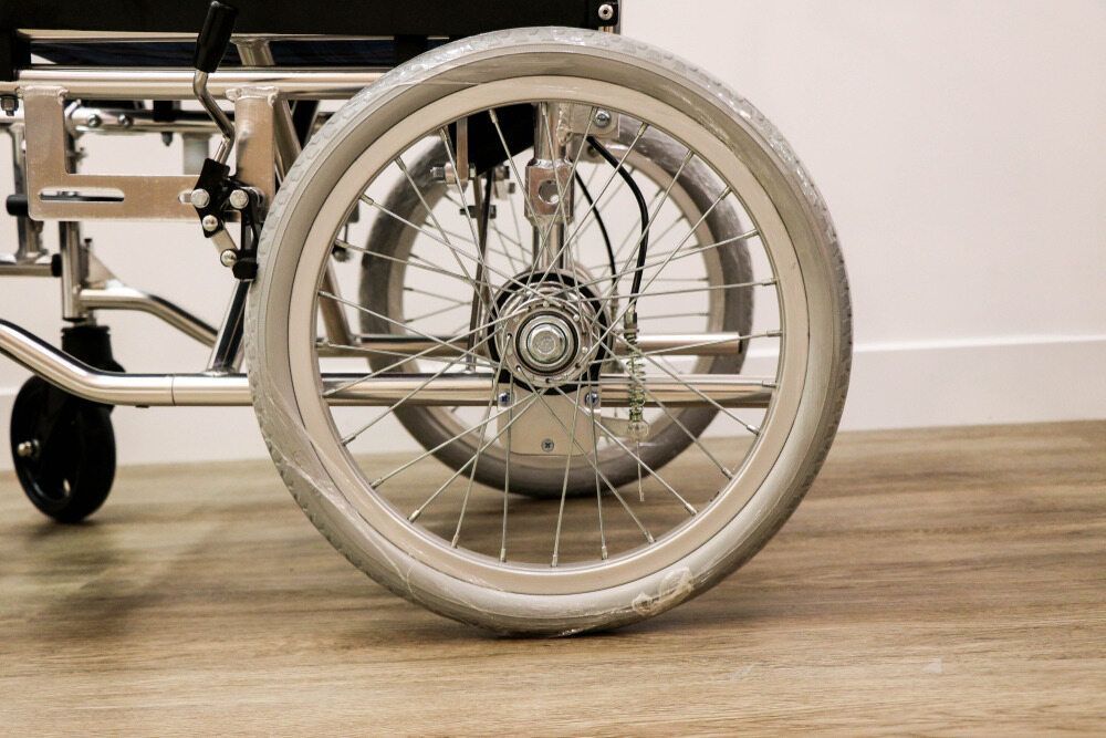 A Close Up of a Wheelchair Wheel on a Wooden Floor — Empowering You Disability Services In Maryborough, QLD