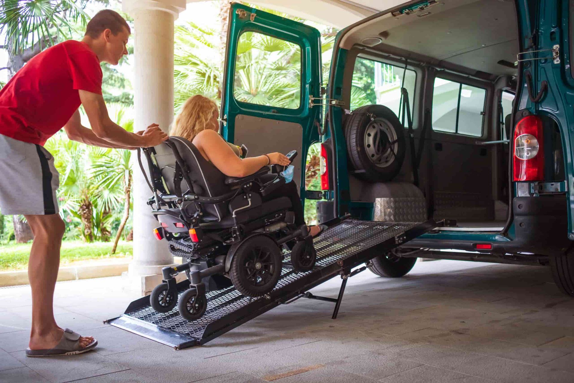 A Man is Helping a Woman in a Wheelchair Into a Van — Empowering You Disability Services In Maryborough, QLD