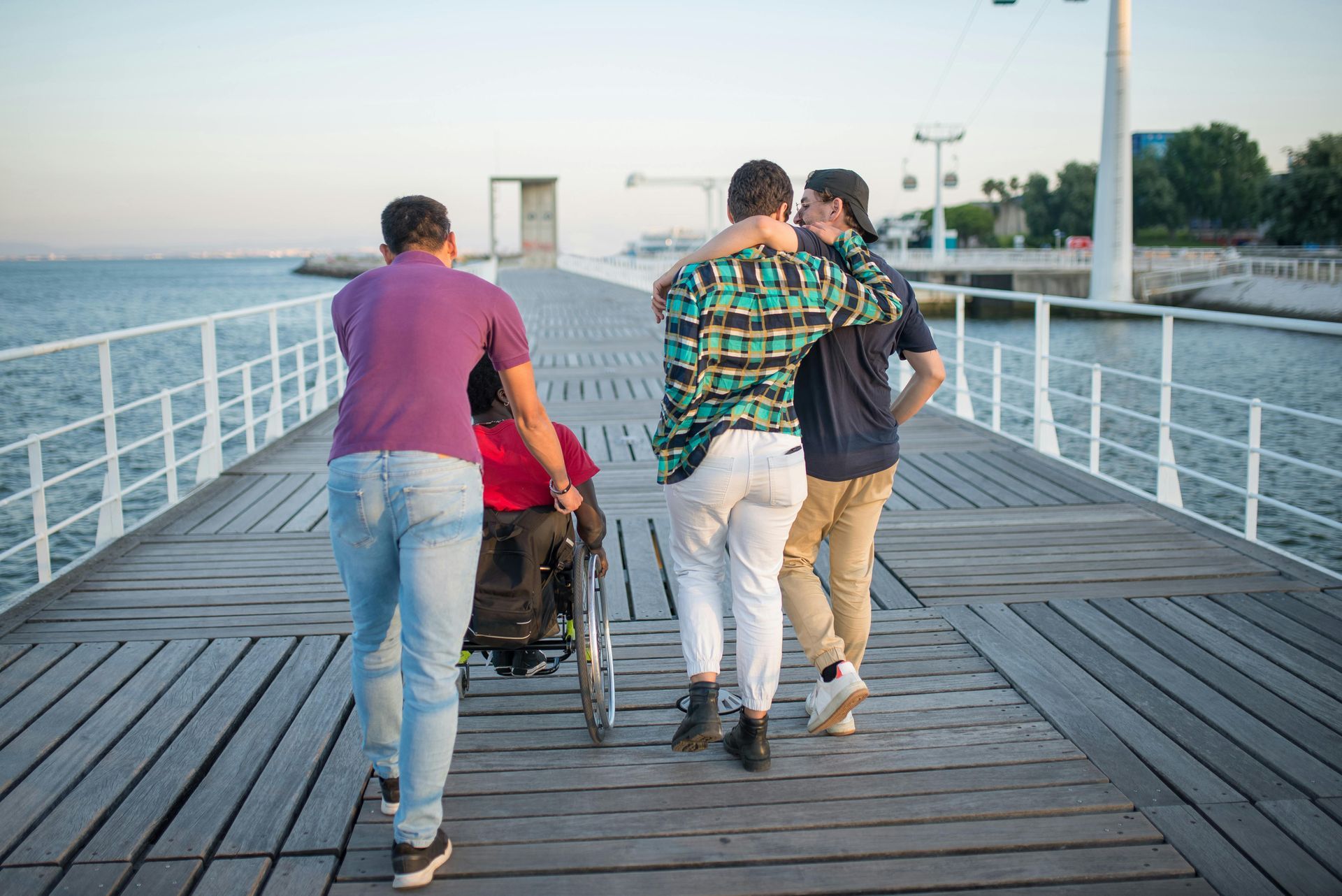 Group of Friends Waking Down a Pier One of Them in a Wheel Chair  — Empowering You Disability Services In Maryborough, QLD