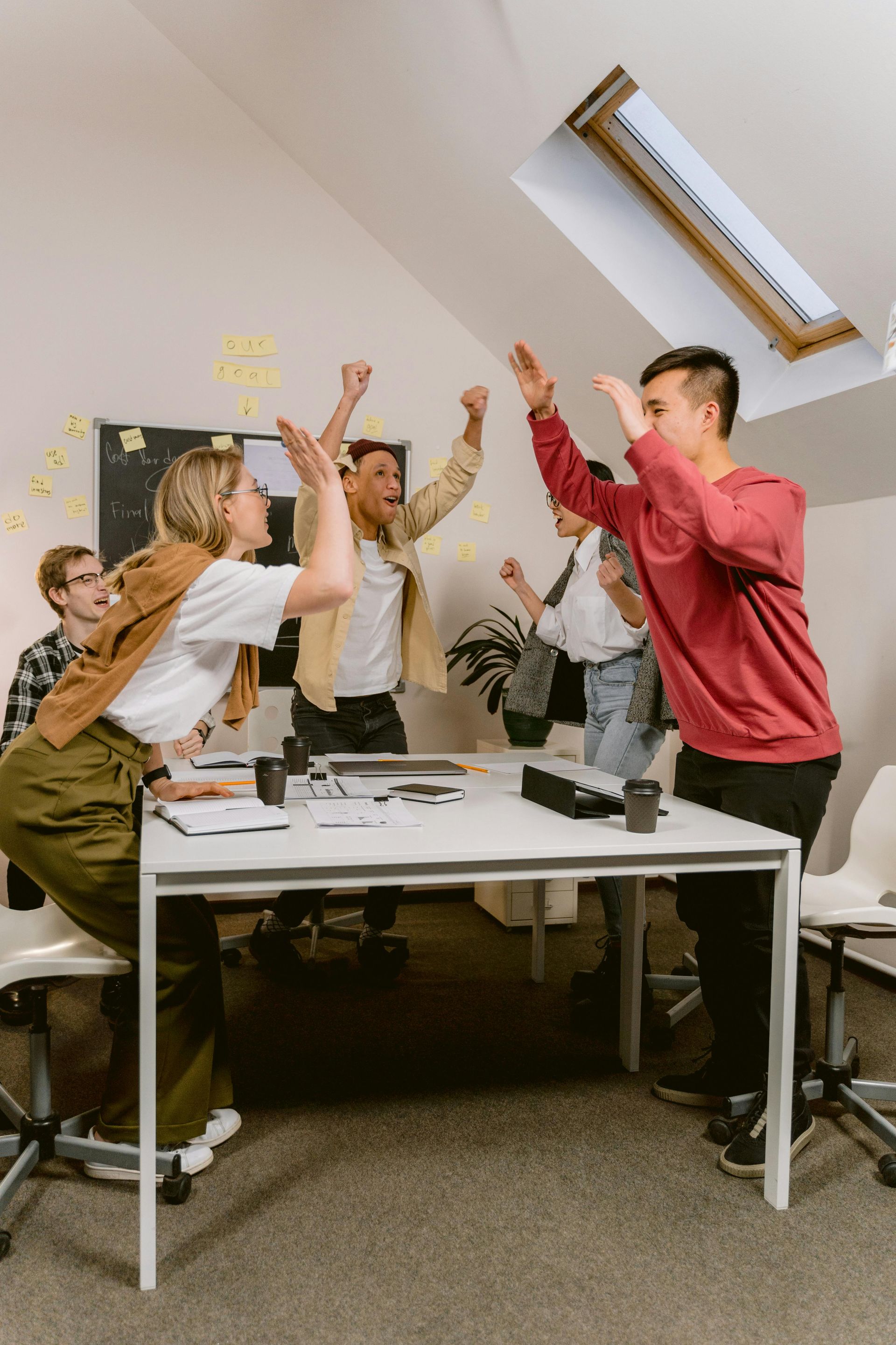 A Group of People Are Giving Each Other a High Five in an Office — Empowering You Disability Services In Maryborough, QLD
