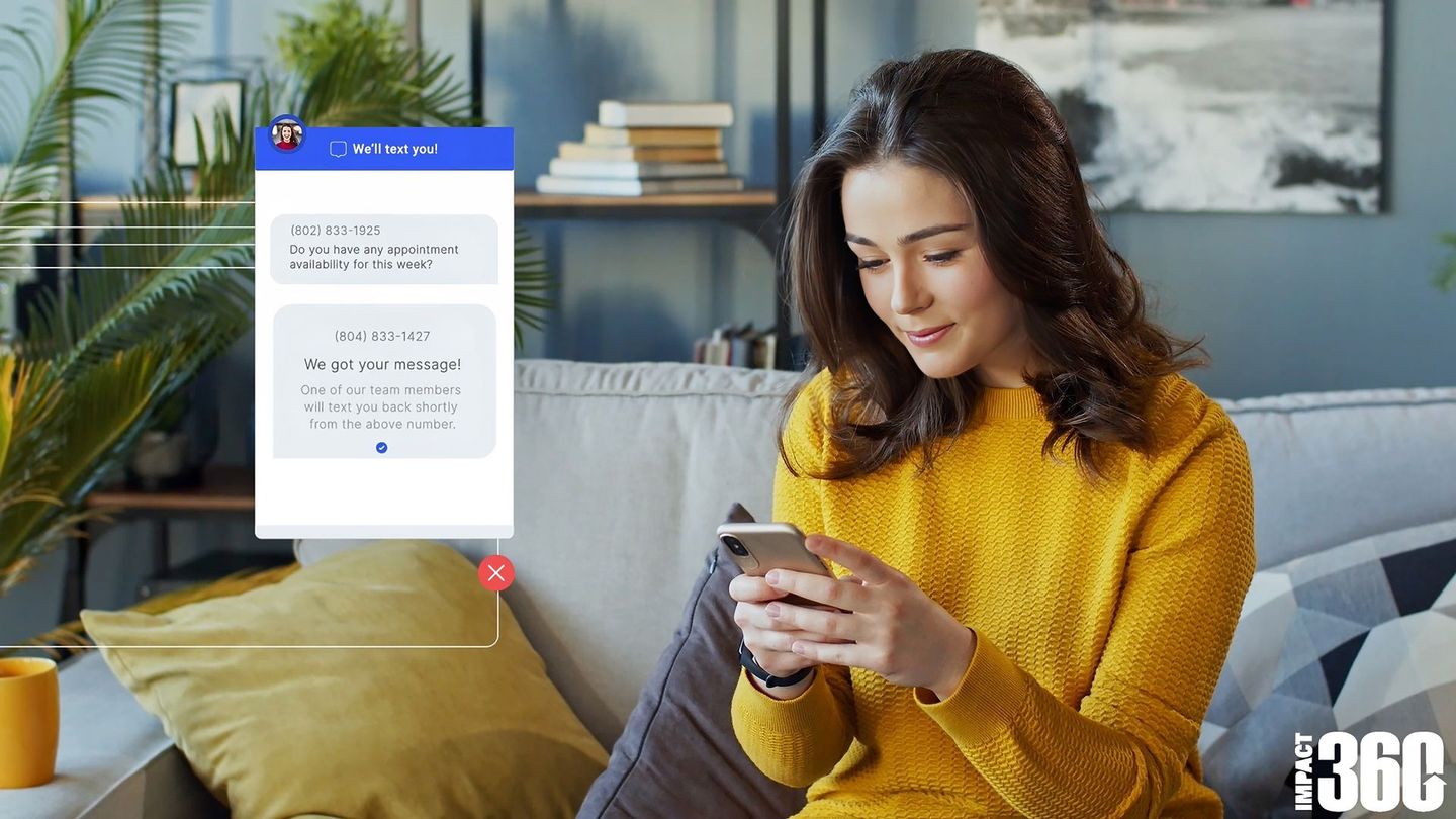 a woman in a yellow sweater is sitting on a couch looking at her phone