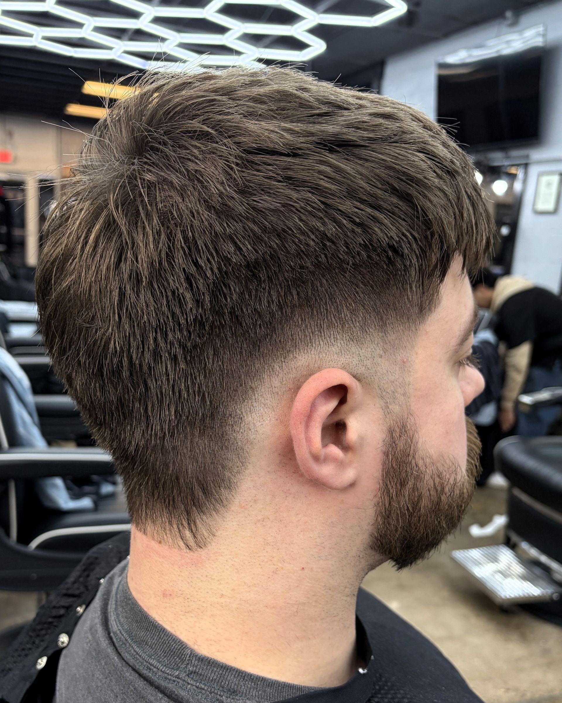 Man with a faded haircut and beard in a barber shop.