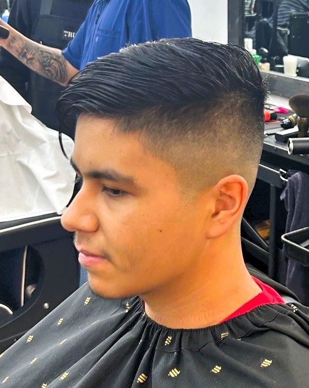Man with a fade haircut, side profile, in a barber shop.