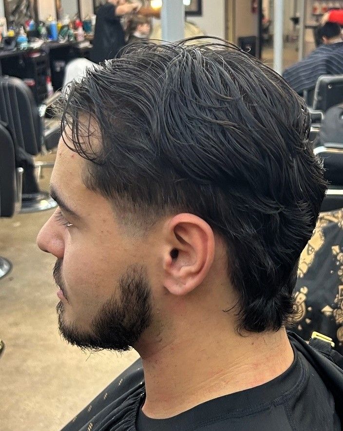 Man with dark hair and a faded haircut, side profile. Sitting in a barber shop.