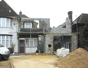 house with extension under construction with scaffolding and breeze blocks and sand around