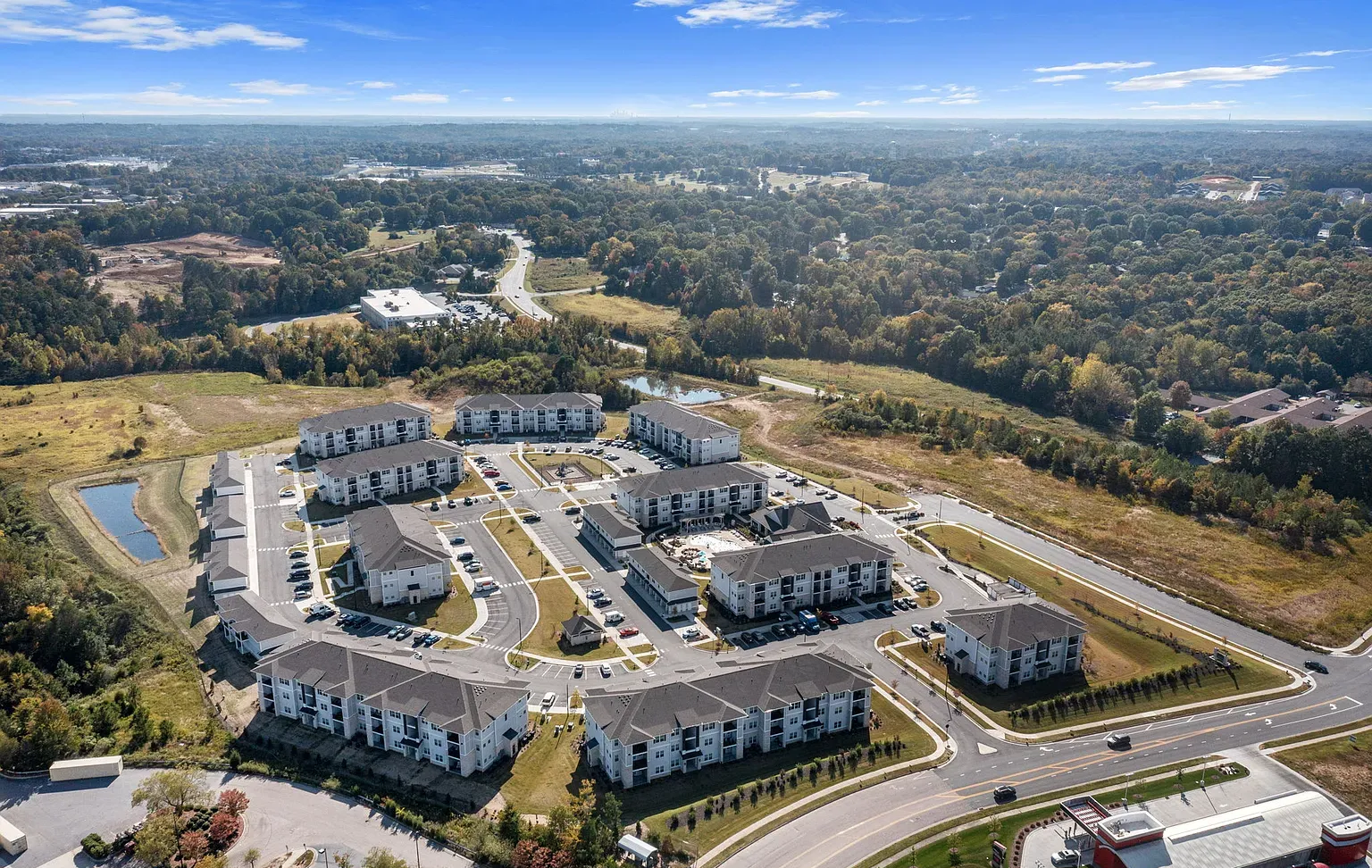 Aerial view of a multi-building apartment community with parking lots and surrounding trees at Graces Reserve Apartments in Kannapolis, NC.