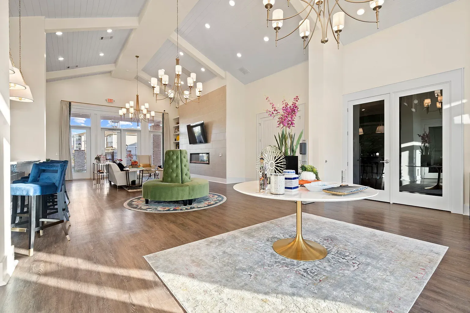 Bright community lounge with seating, chandeliers, and glass doors at Graces Reserve Apartments in Kannapolis, NC.
