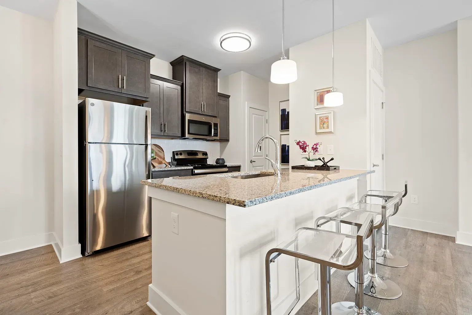 Modern apartment kitchen with granite island, stainless steel appliances, and bar stools at Graces Reserve Apartments in Kannapolis, NC.