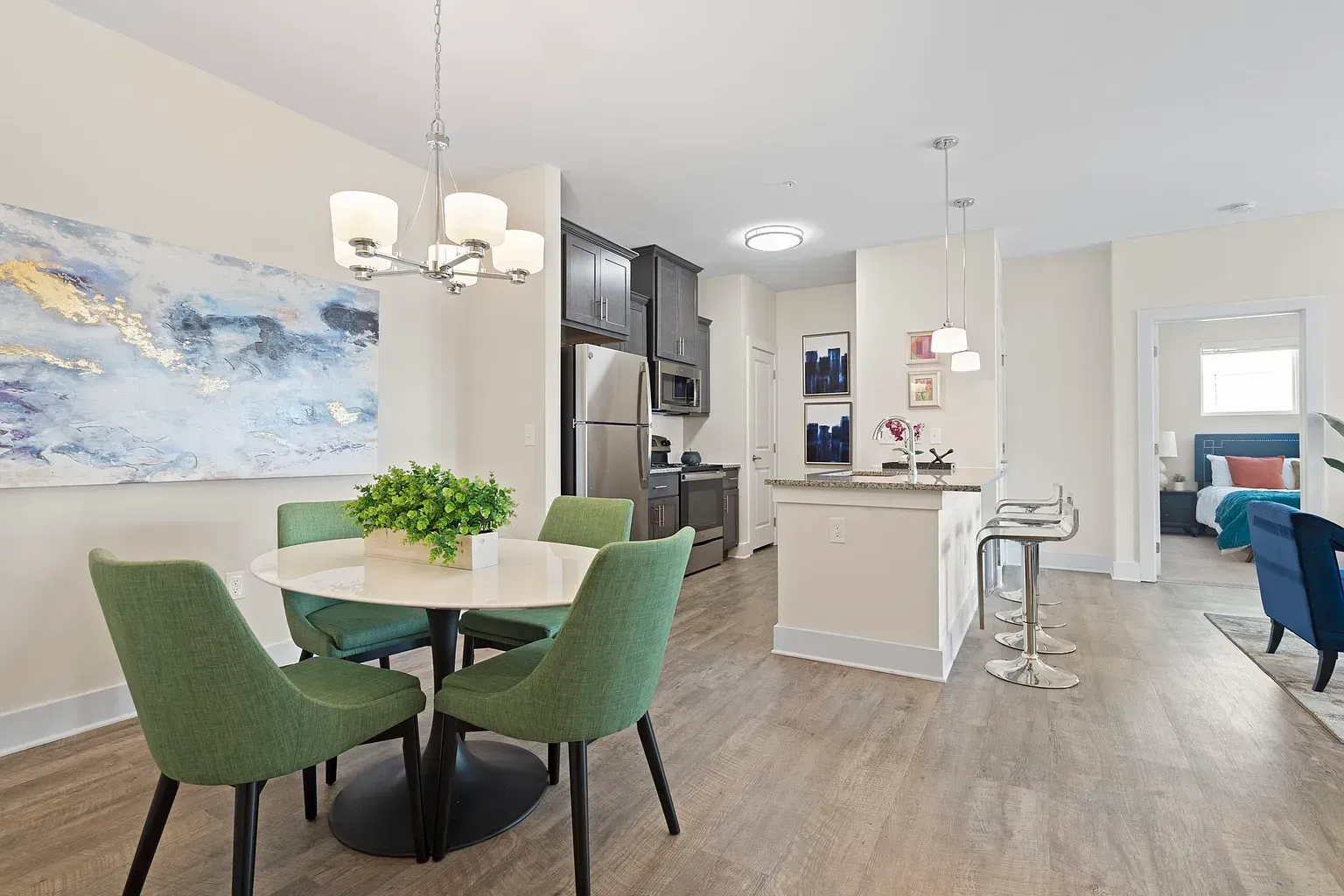 Open-concept apartment interior featuring a dining area with green chairs and a modern kitchen at Graces Reserve Apartments in Kannapolis, NC.