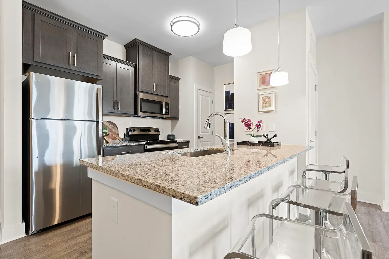 Modern kitchen in an apartment with a granite island, stainless steel appliances, and bar stools at Graces Reserve Apartments in Kannapolis, NC.