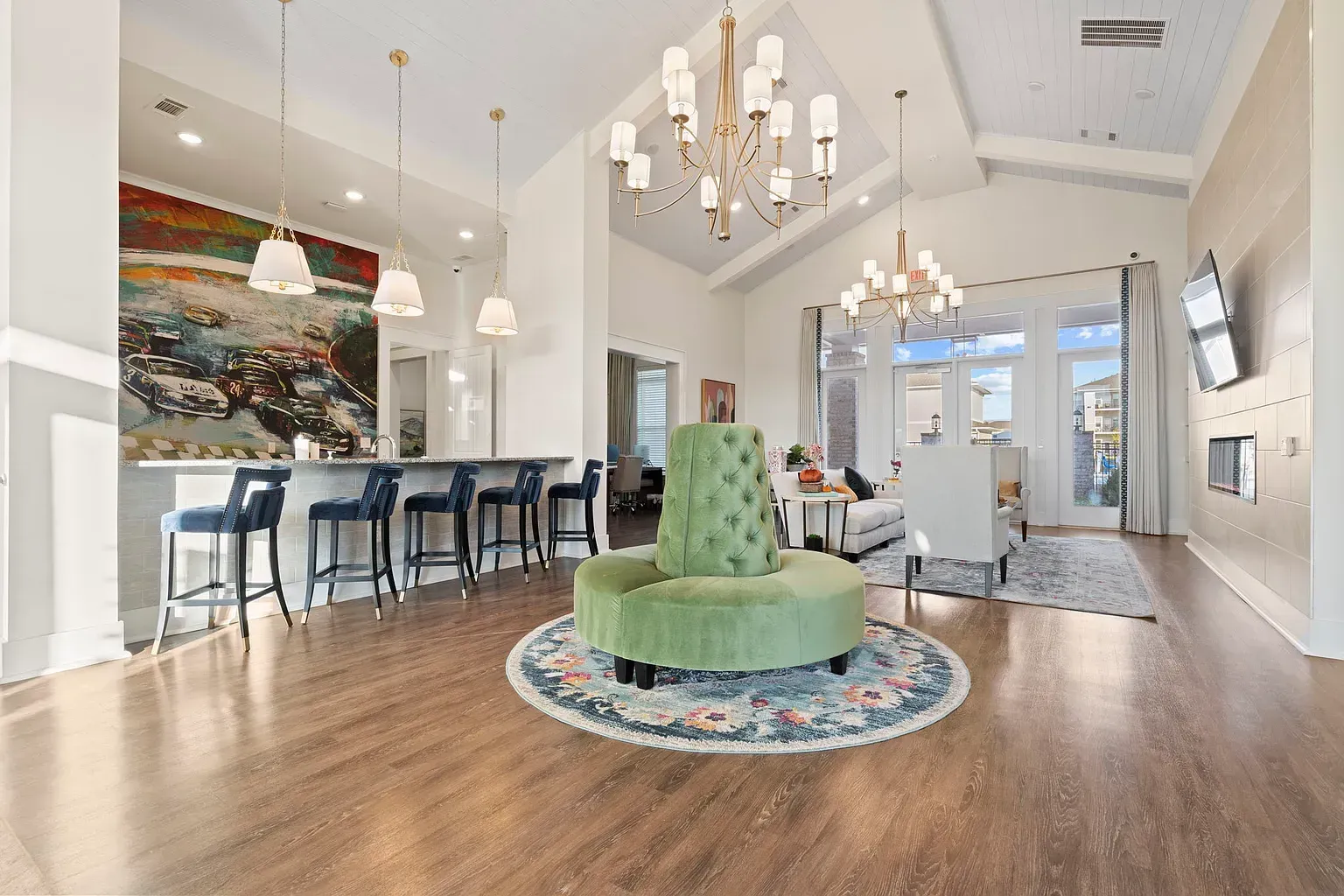 Bright modern lounge with a bar, seating, chandeliers, and a wall-mounted TV at Graces Reserve Apartments in Kannapolis, NC.