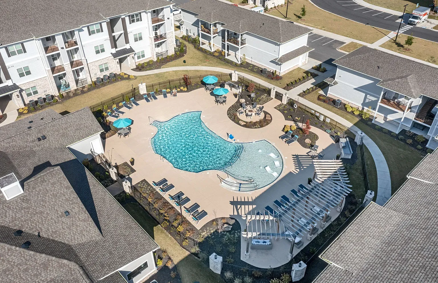 Aerial view of a resort-style apartment community pool with lounge chairs and umbrellas at Graces Reserve Apartments in Kannapolis, NC.
