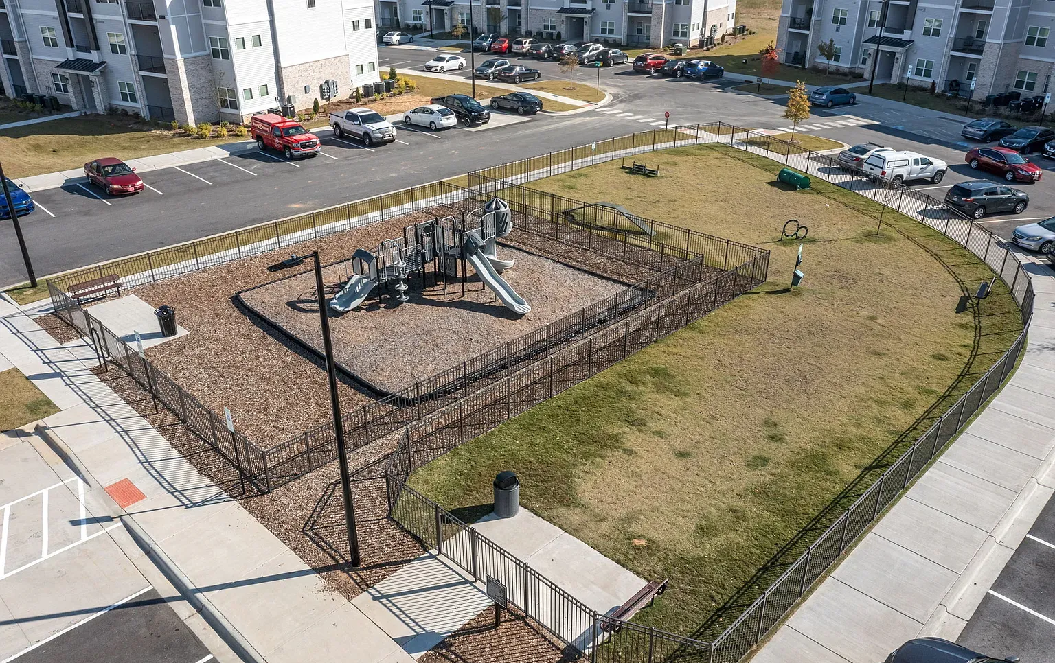 Aerial view of a fenced playground with slides in a residential complex at Graces Reserve Apartments in Kannapolis, NC.