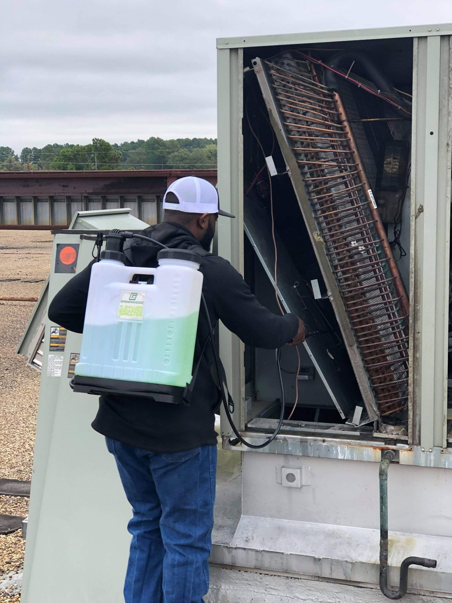A man with a backpack is spraying a machine with a sprayer.