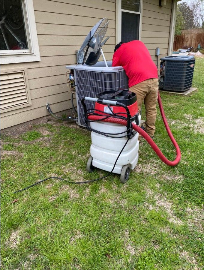 A man is cleaning an air conditioner with a vacuum cleaner.