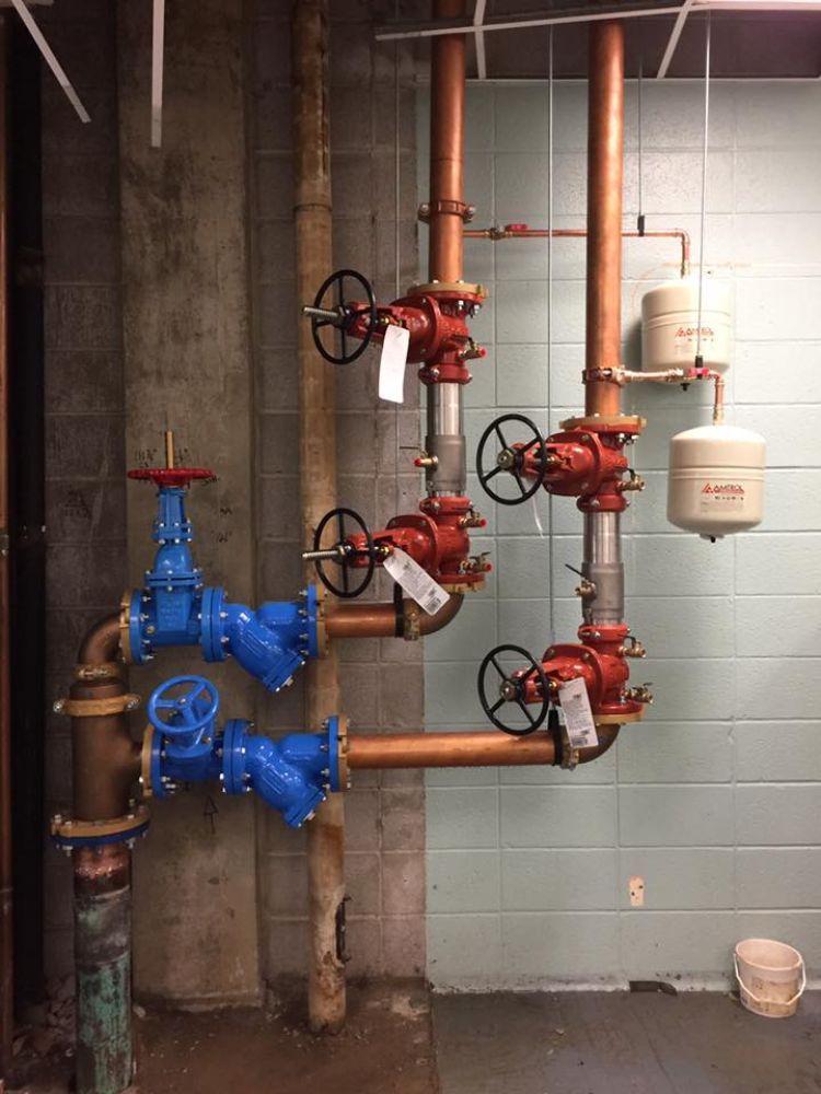 A room with a lot of pipes and valves hanging from the ceiling.
