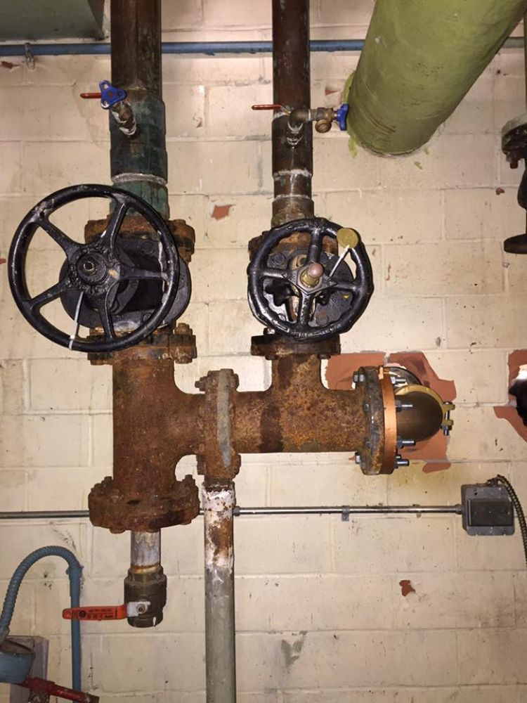 A close up of a rusty pipe with two valves on it