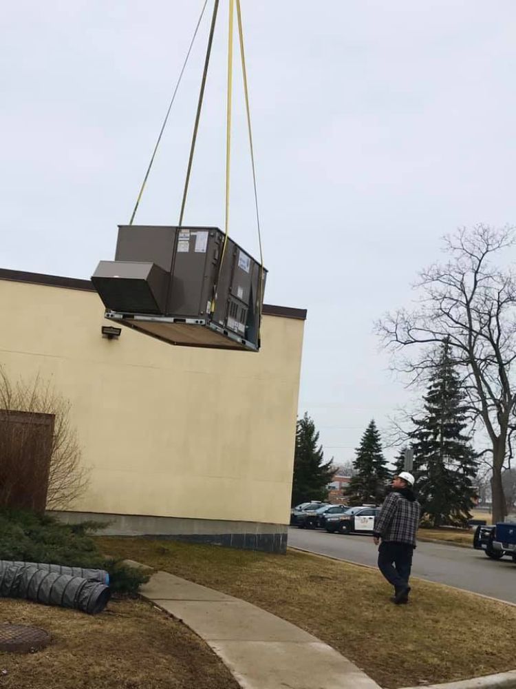 A crane is lifting a large box from the side of a building.