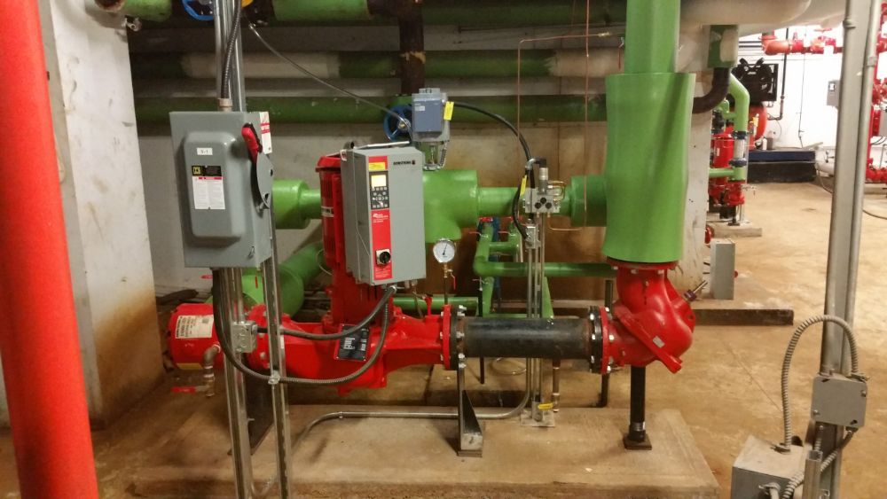 A room filled with green pipes and red pumps.