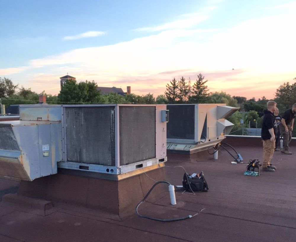 A group of people standing on top of a roof with a sunset in the background.