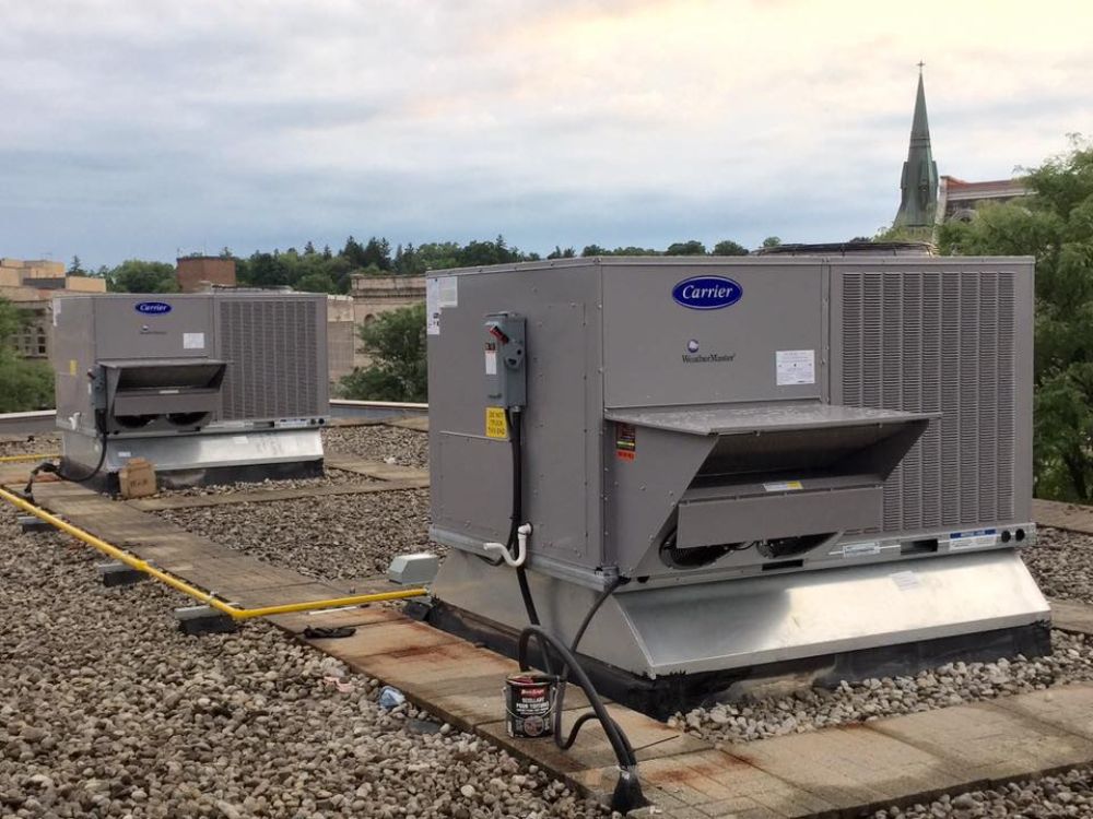 Two air conditioners are sitting on top of a roof.