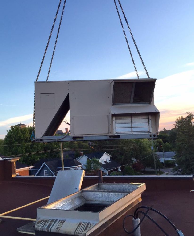 A crane is lifting a large box on top of a roof