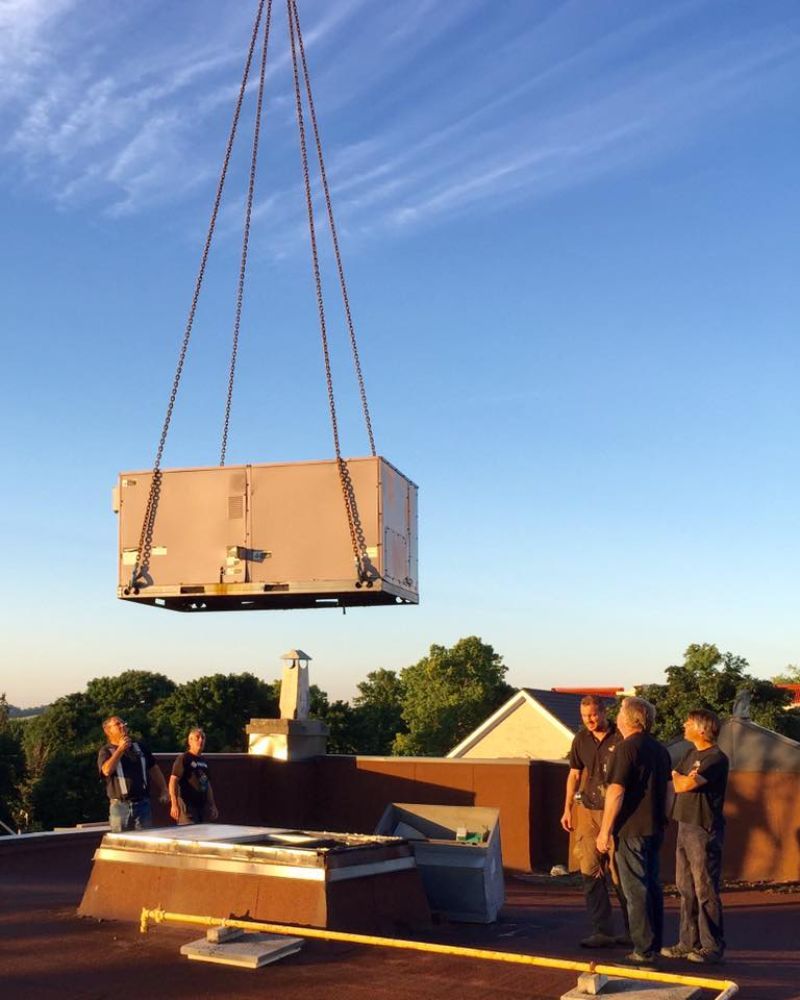 A large box is being lifted by a crane on top of a building