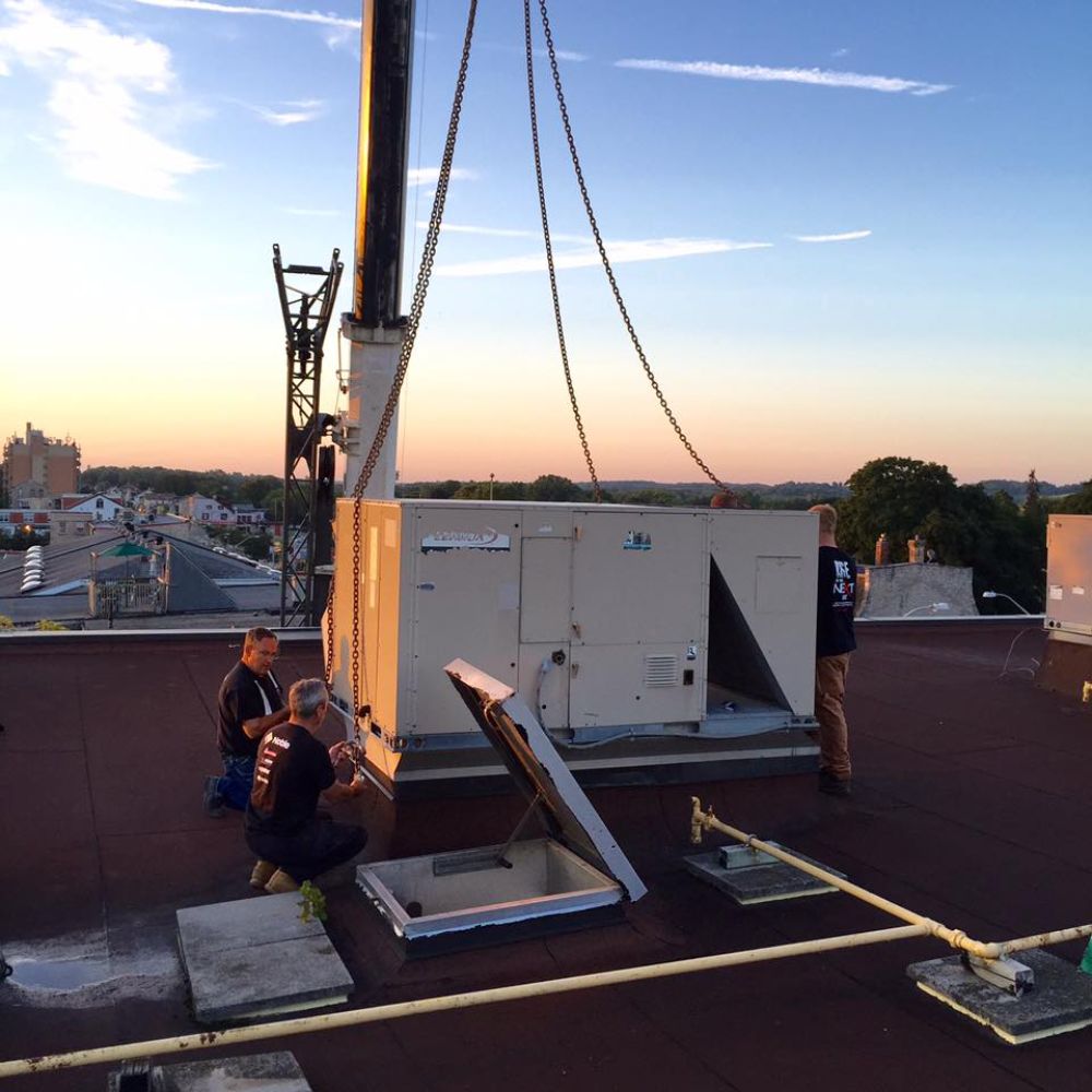 A group of men are working on a roof with a crane in the background