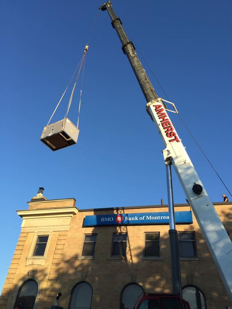 A crane is lifting a box in front of a budweiser sign