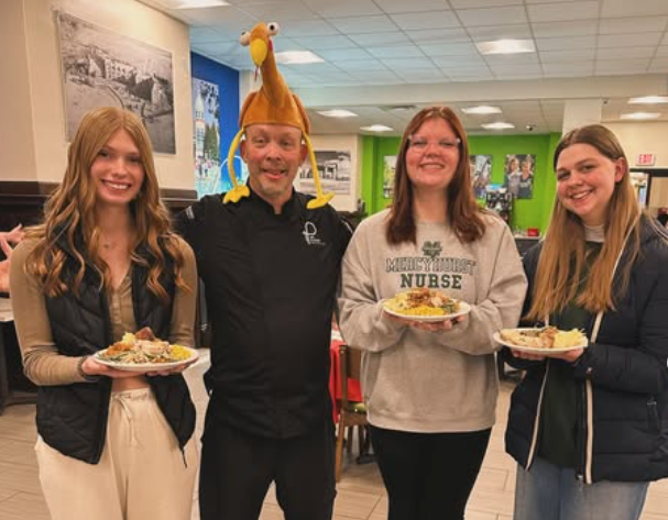4 Students holding food one with a turkey hat