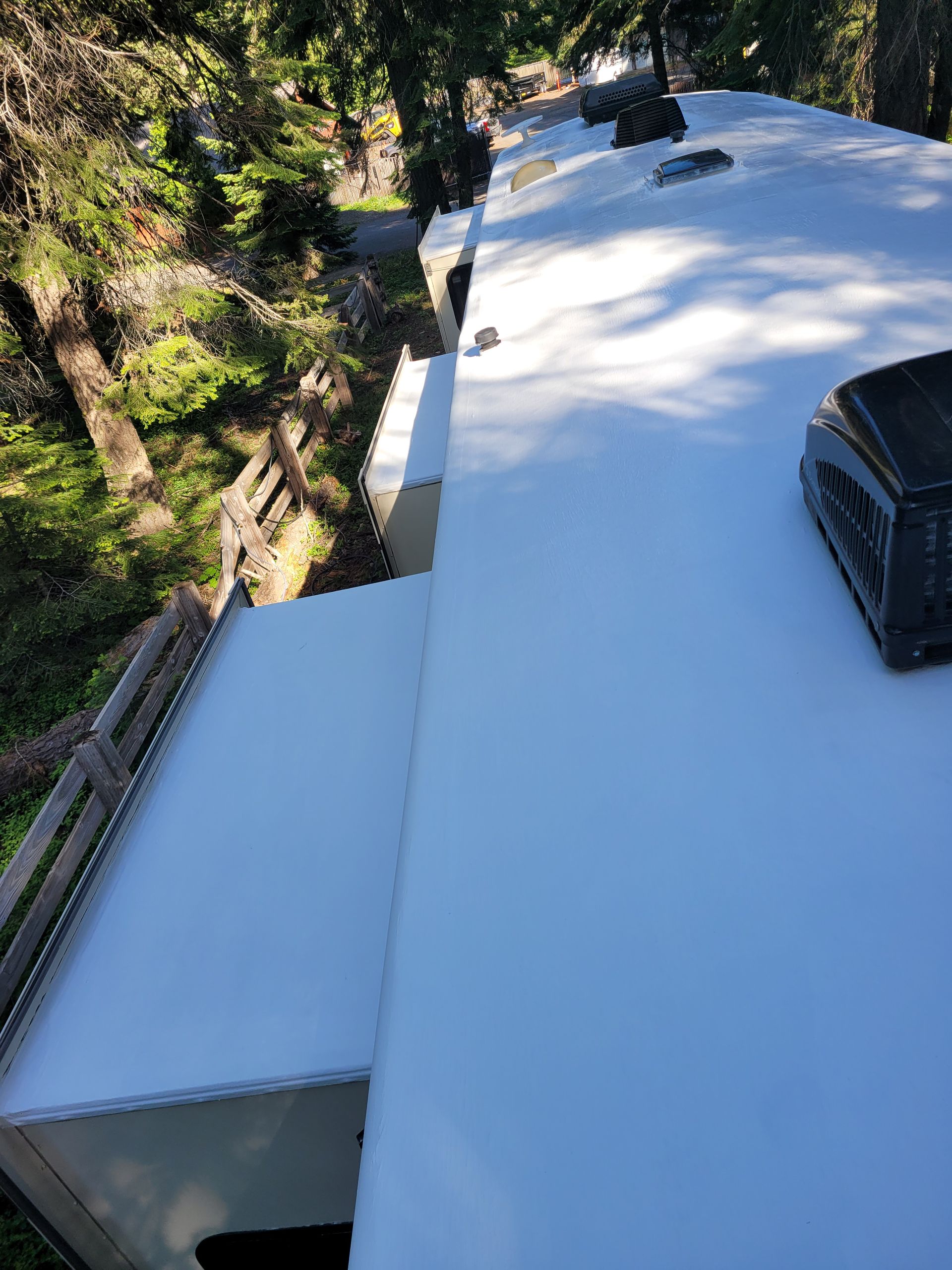 A white roof of a rv with trees in the background.