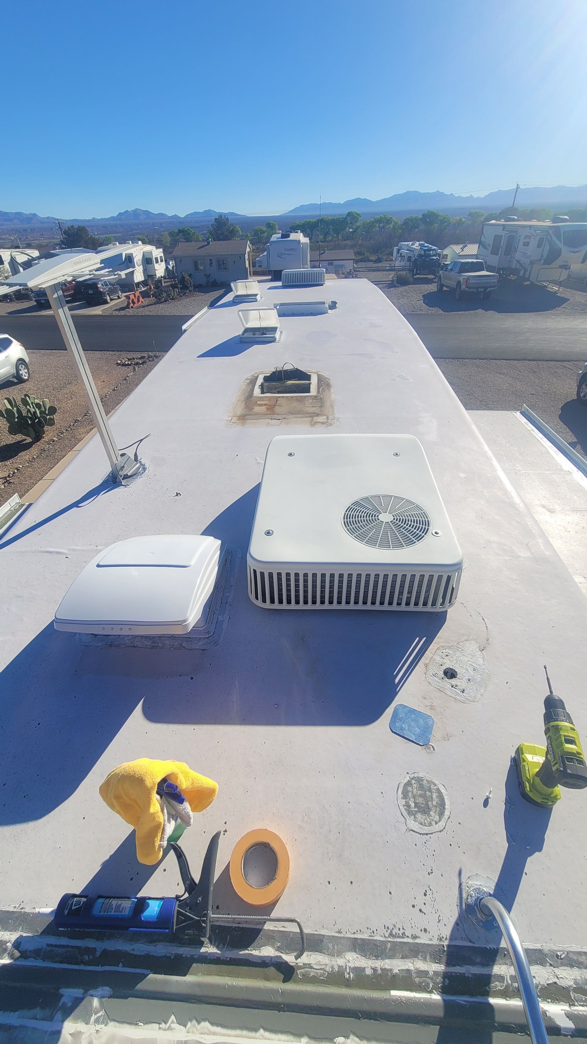 Workers on a rooftop installing equipment under a bright sky, with mountains in the distance.