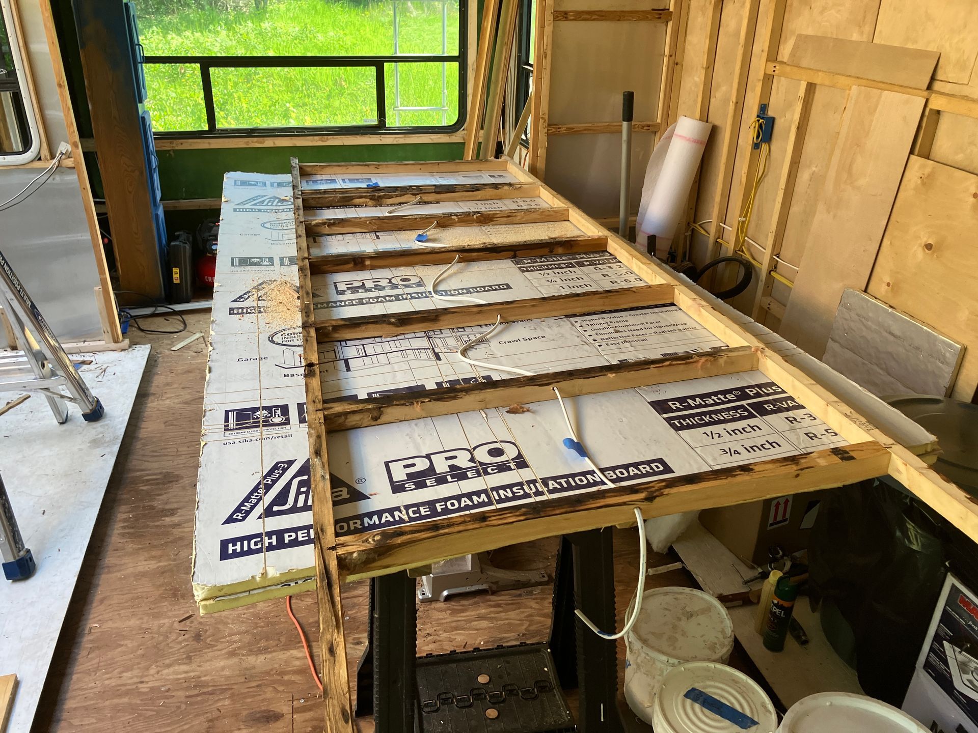 A wooden table is being built in a room with a ladder.