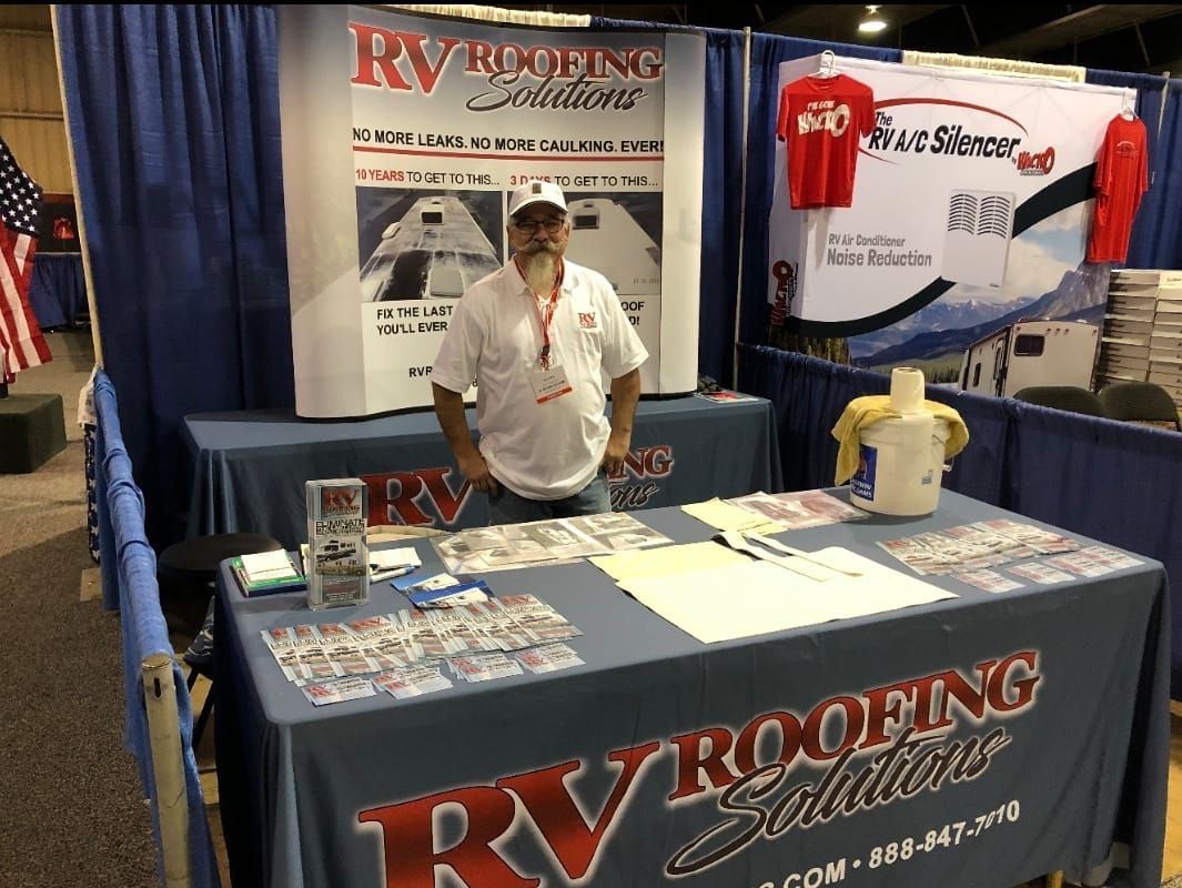 A man is standing in front of a table that says rv roofing solutions