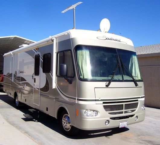 A large rv is parked in front of a garage