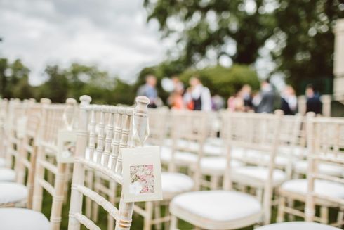 A row of white chairs are lined up for a wedding ceremony.