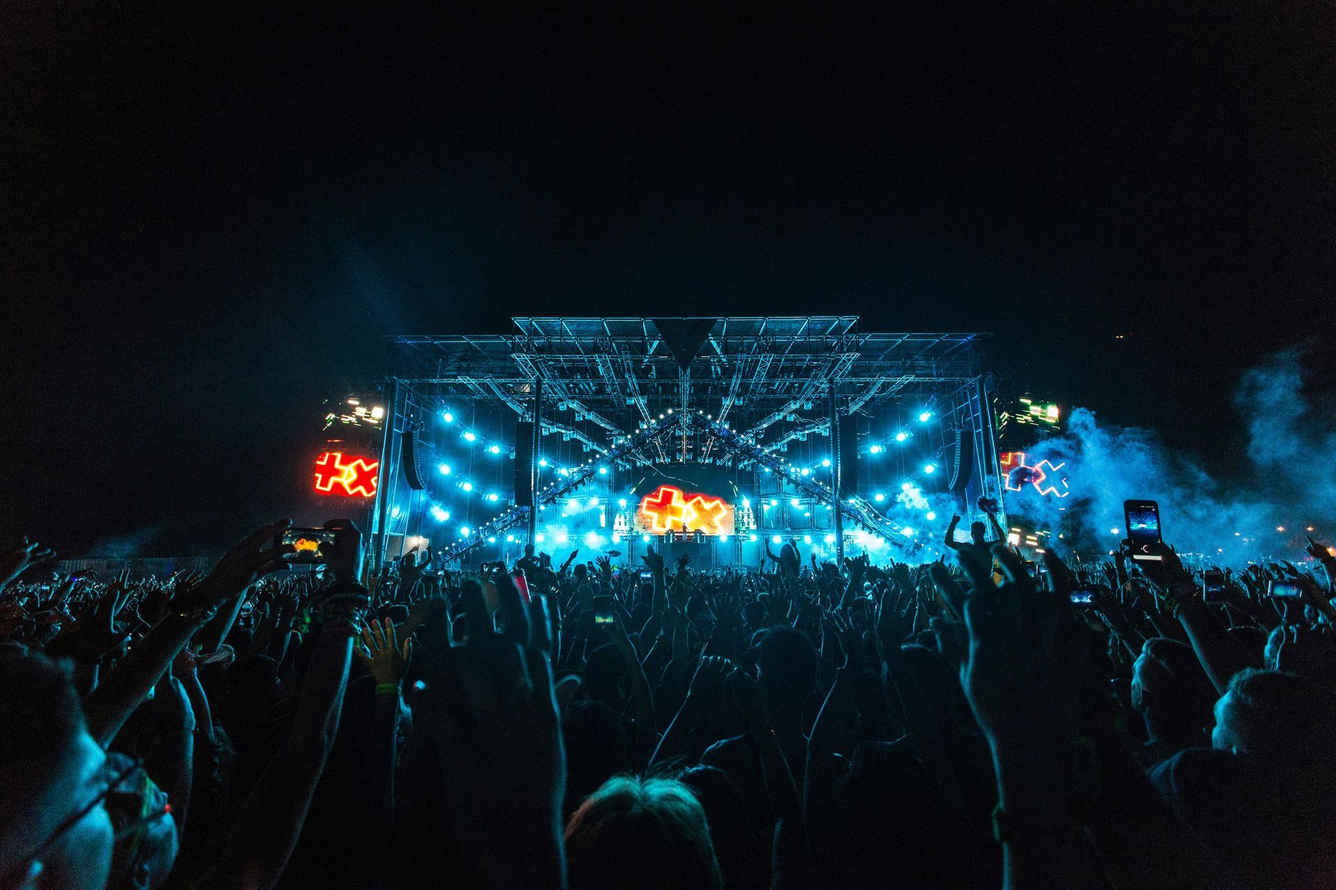 A crowd of people are standing in front of a stage at a concert.