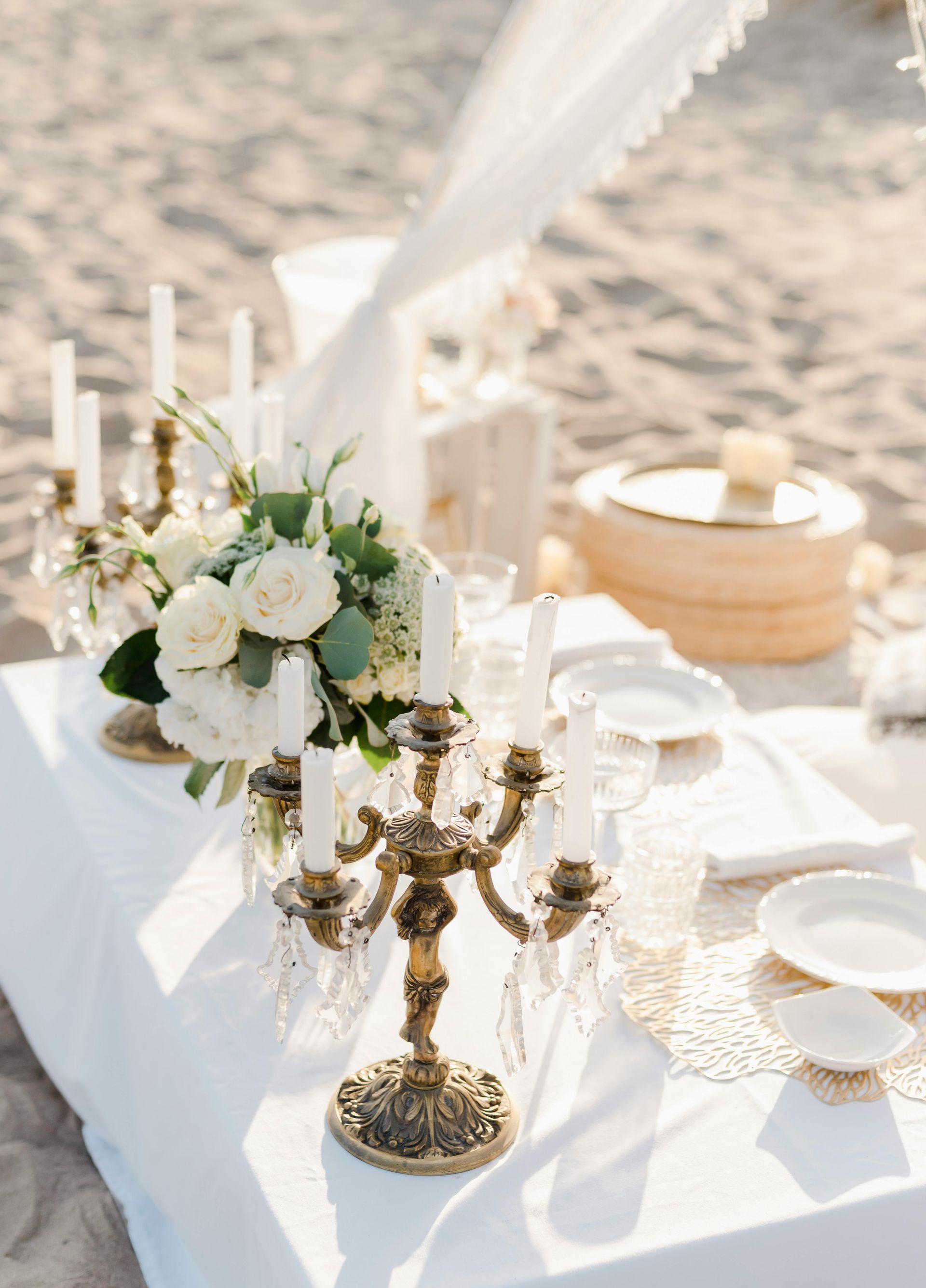A table with candles and flowers on it on the beach.