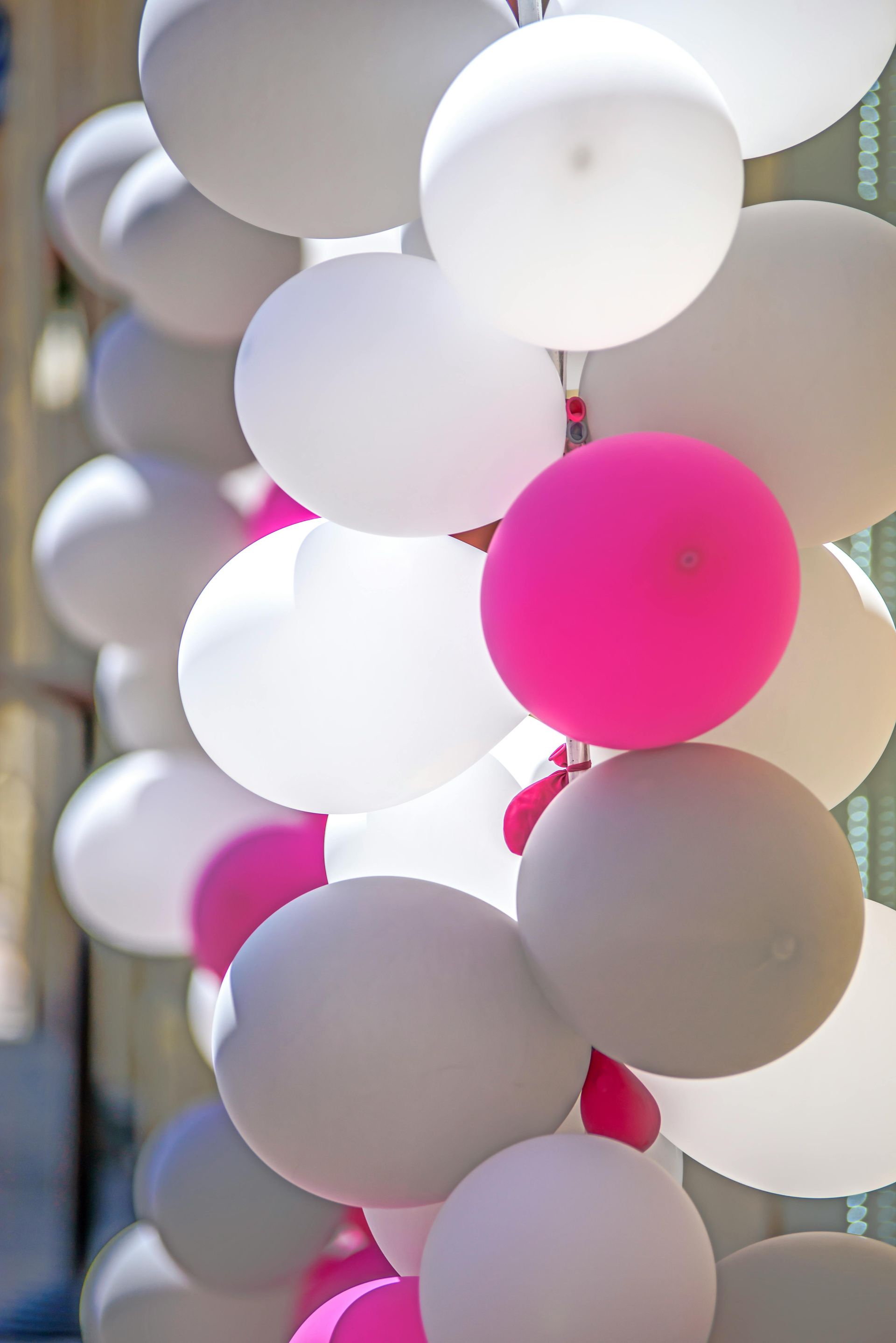 A bunch of white and pink balloons hanging from a string