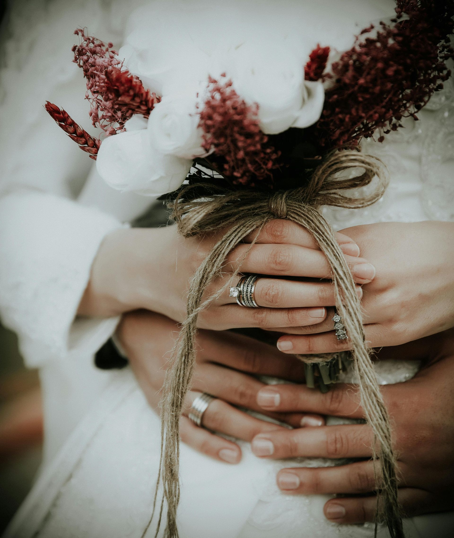 A bride and groom are holding a bouquet of flowers in their hands.