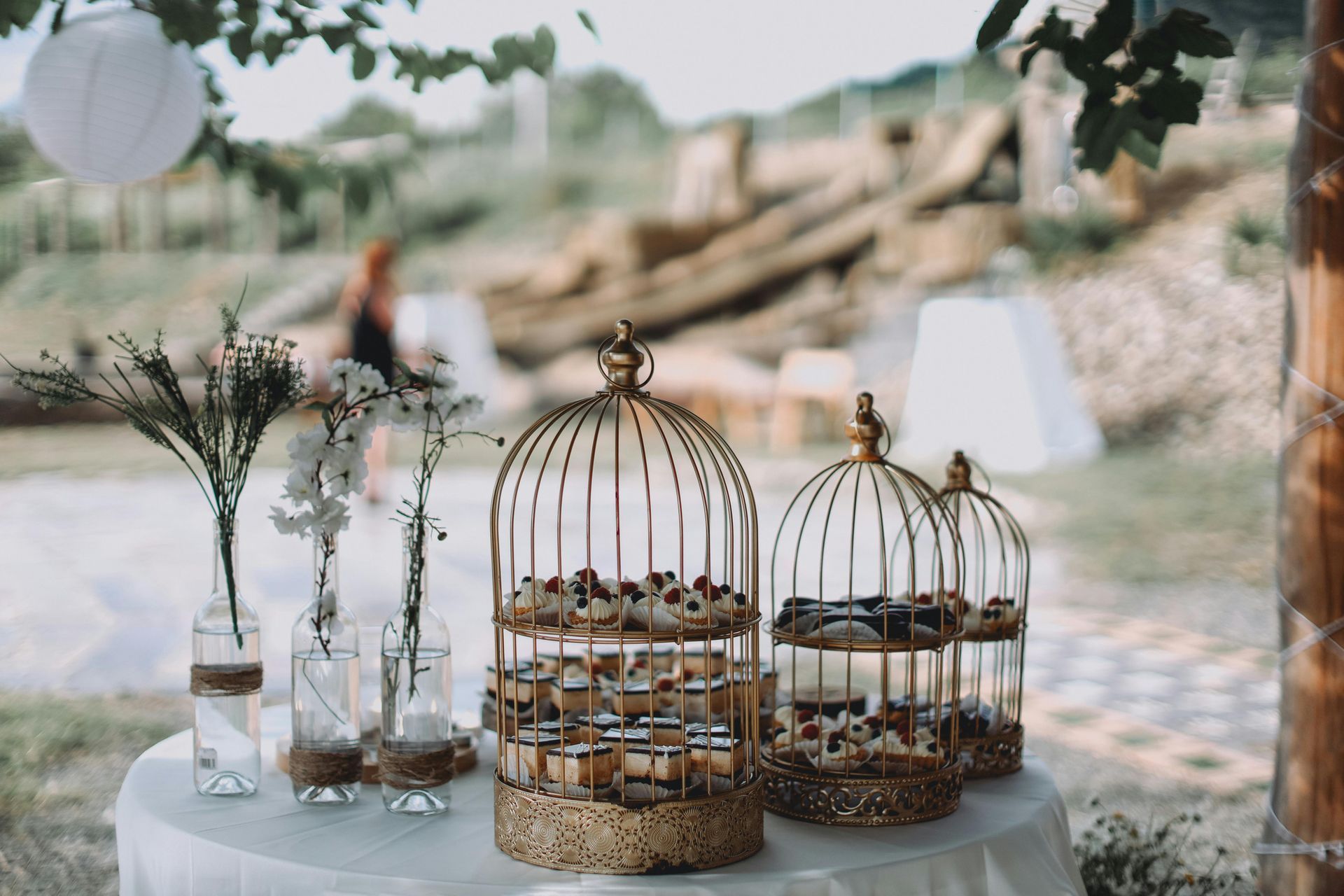 A table with three bird cages filled with cupcakes on it.