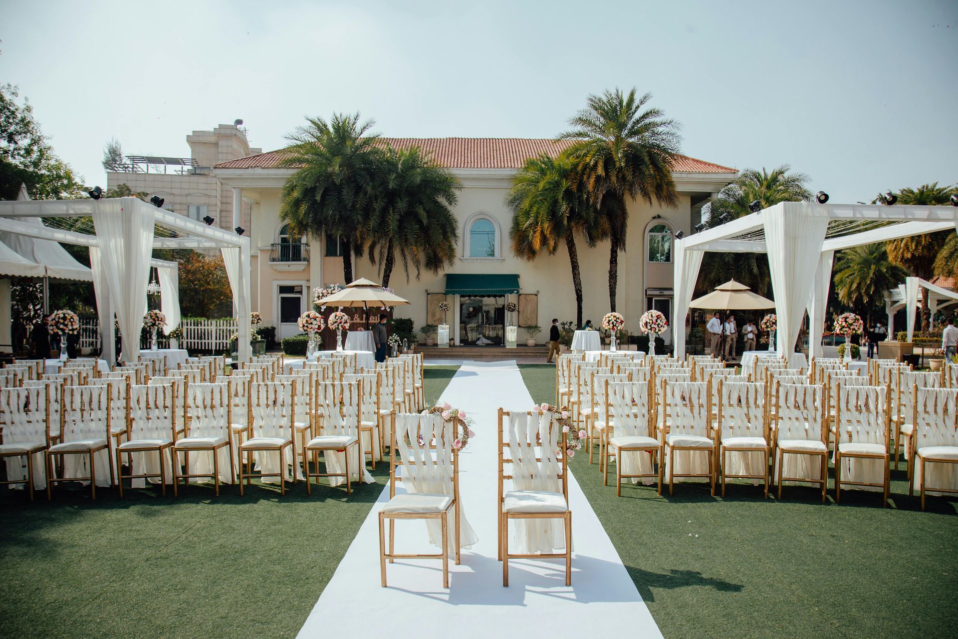 A row of chairs are lined up in front of a large building for a wedding ceremony.