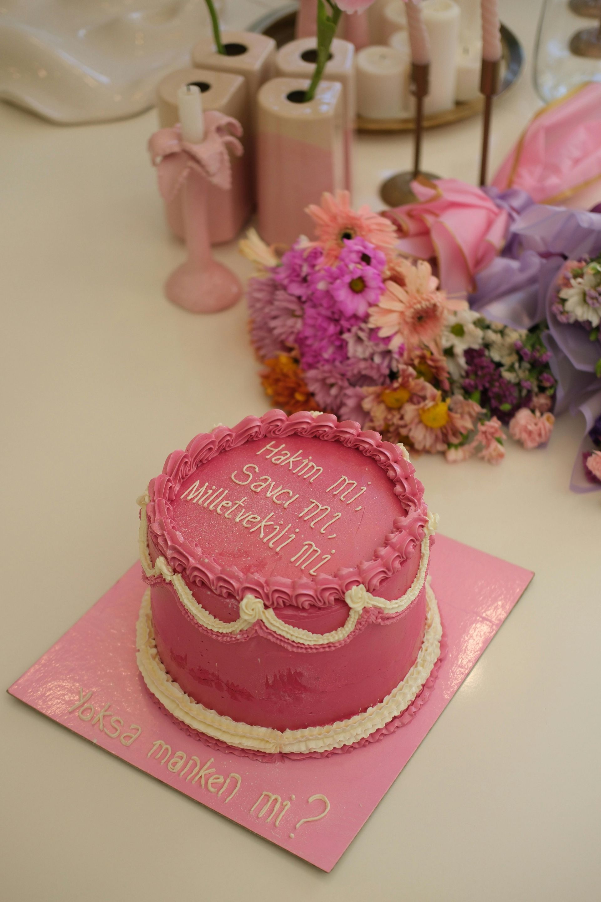 A pink cake is sitting on top of a pink plate on a table.