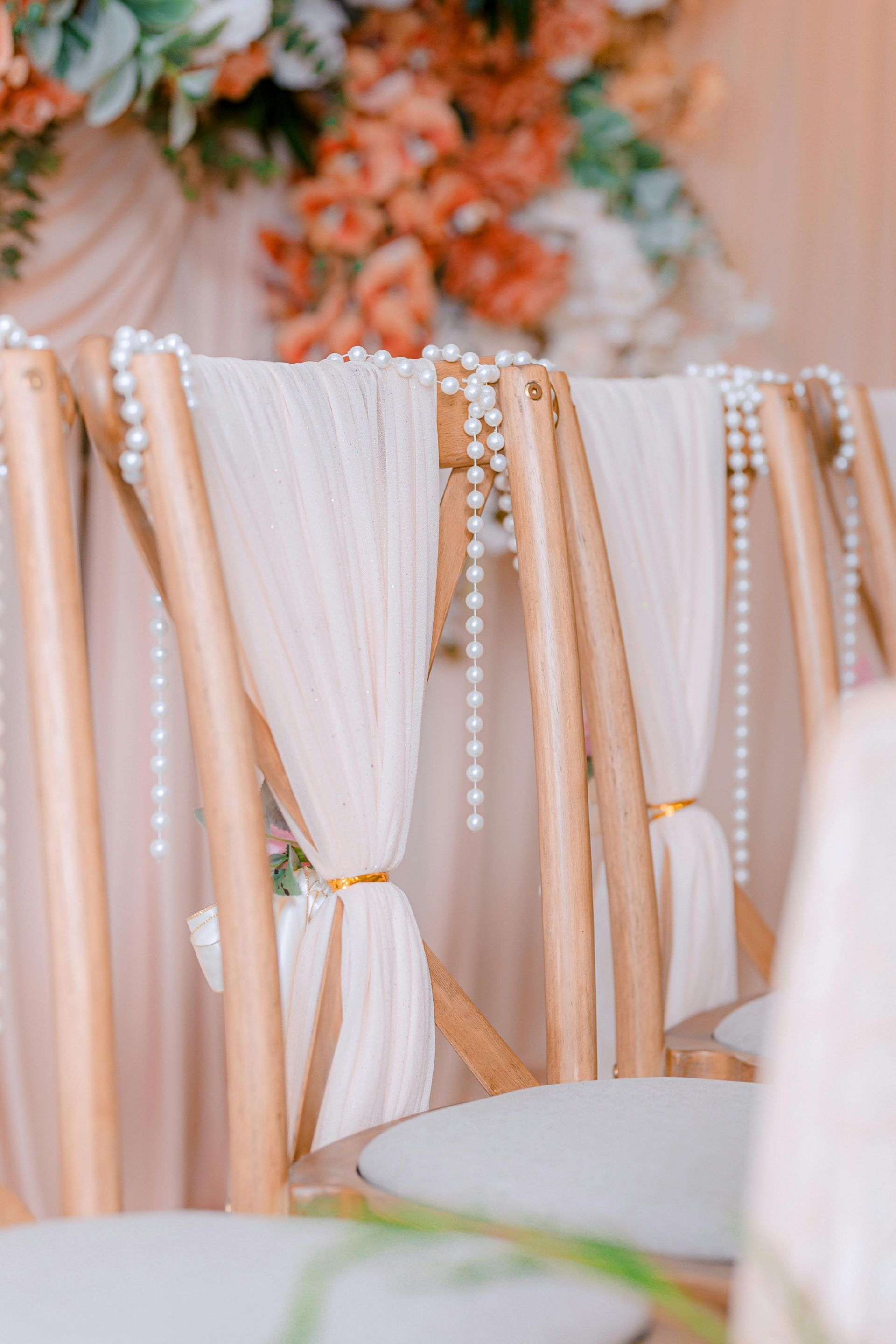 A row of wooden chairs decorated with pearls and flowers.