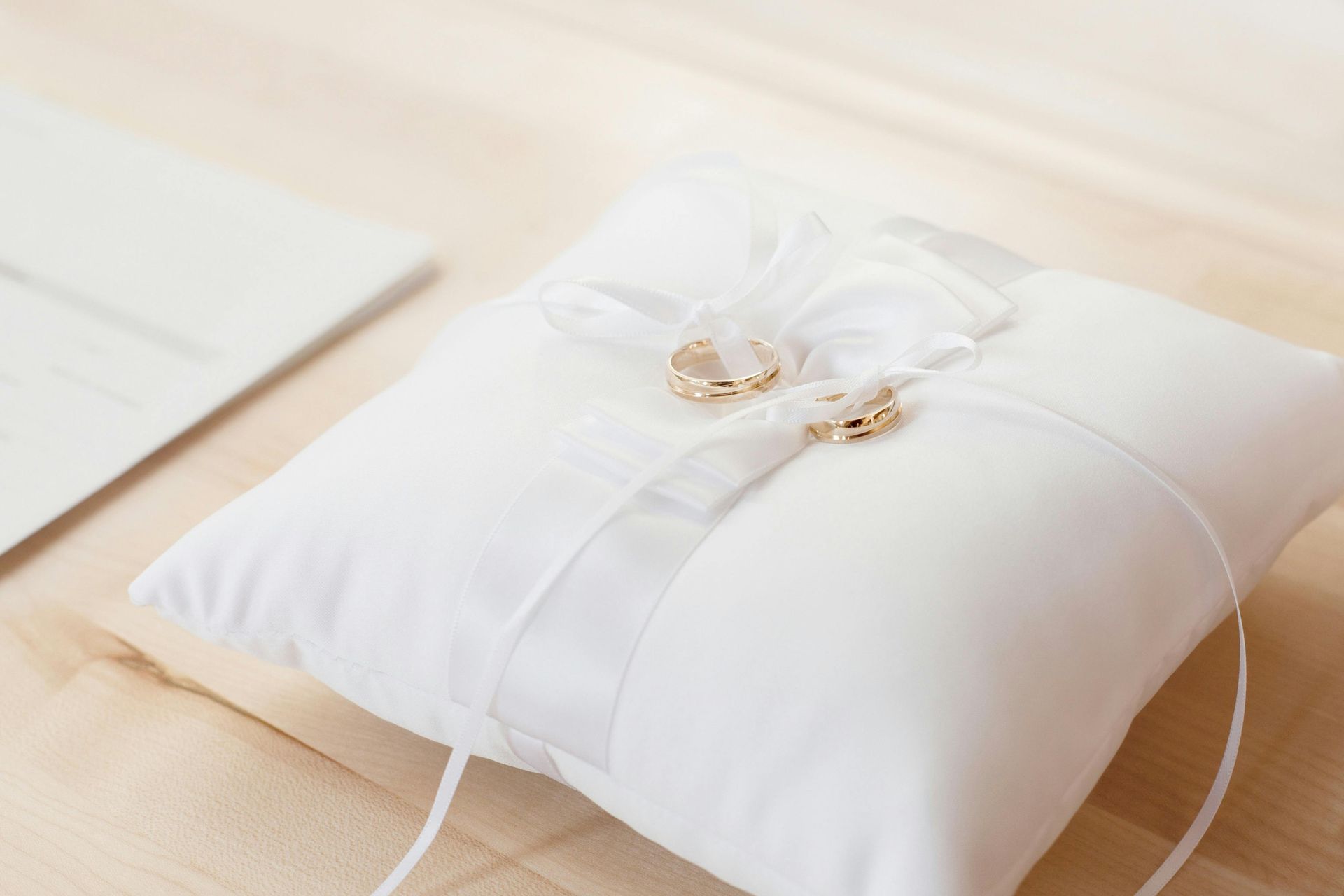 A white pillow with a pair of wedding rings on it.
