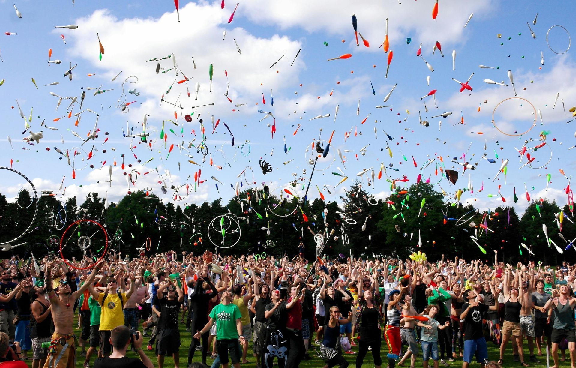A crowd of people standing in a field with confetti falling from the sky