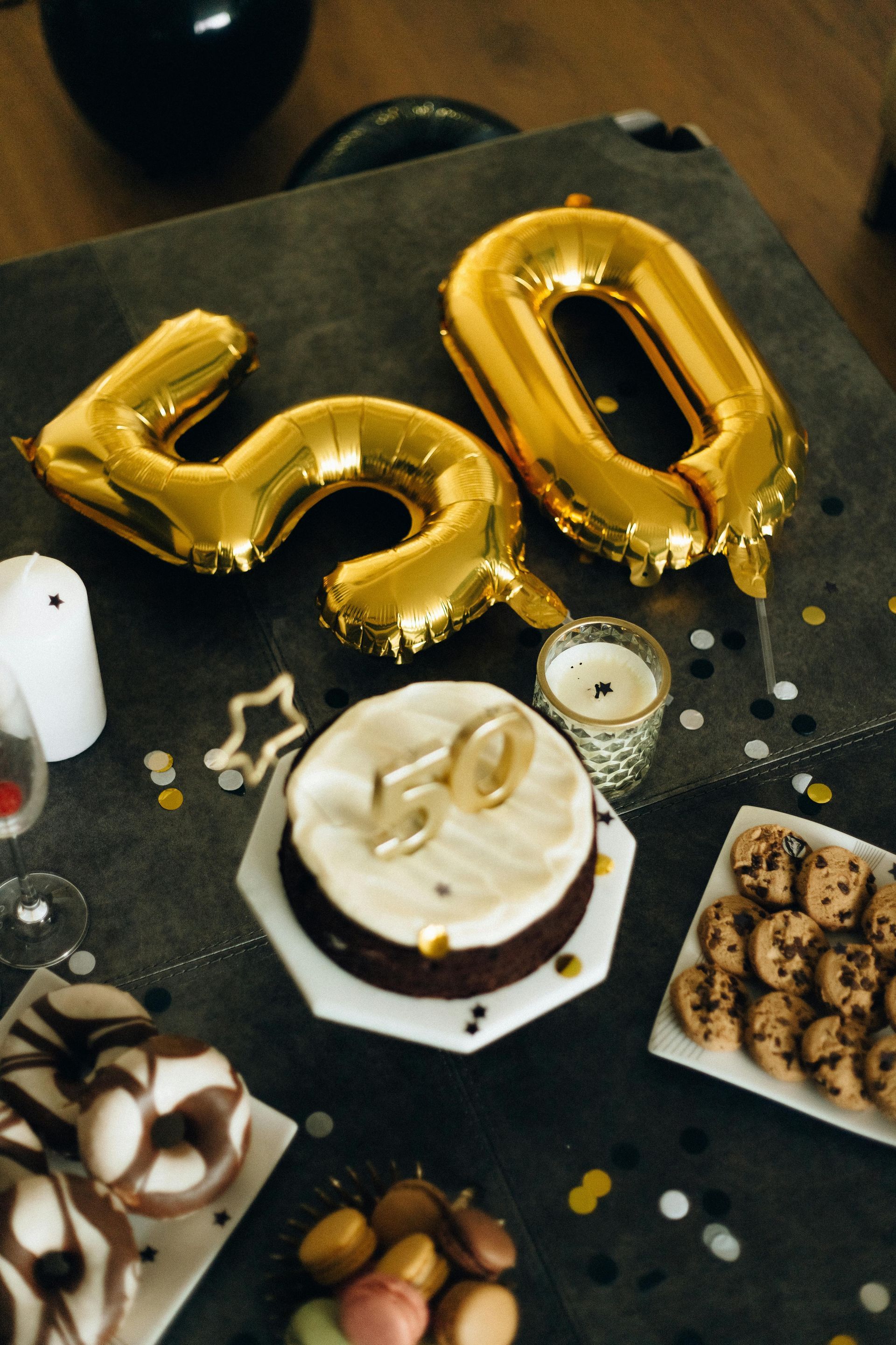 A table with a cake and balloons that say 50